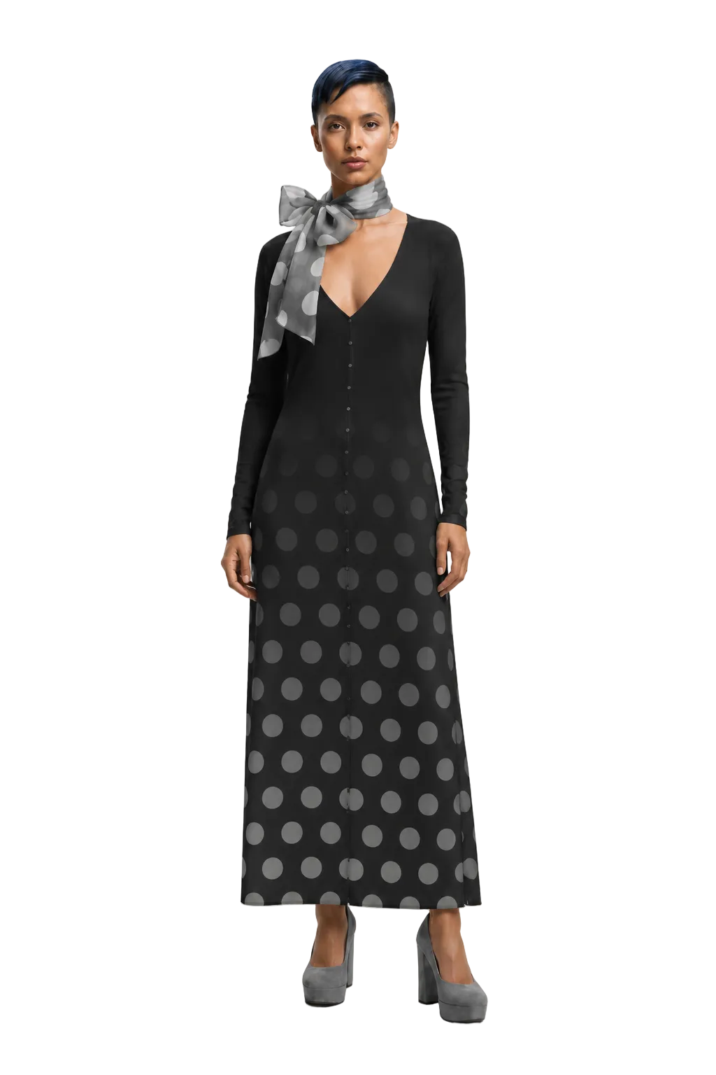 A woman modeling a long-sleeve black maxi dress with a gray polka dot pattern and a matching gray neck scarf, standing against a light gray studio background.