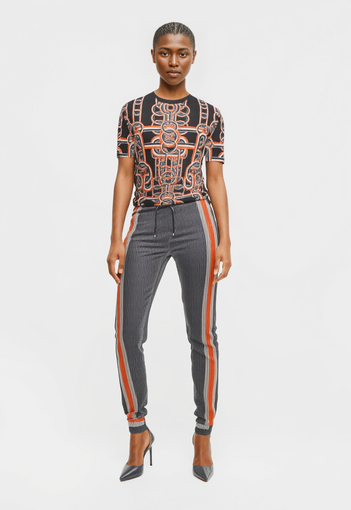 Woman wearing a patterned top and gray pants with orange stripes on a white background